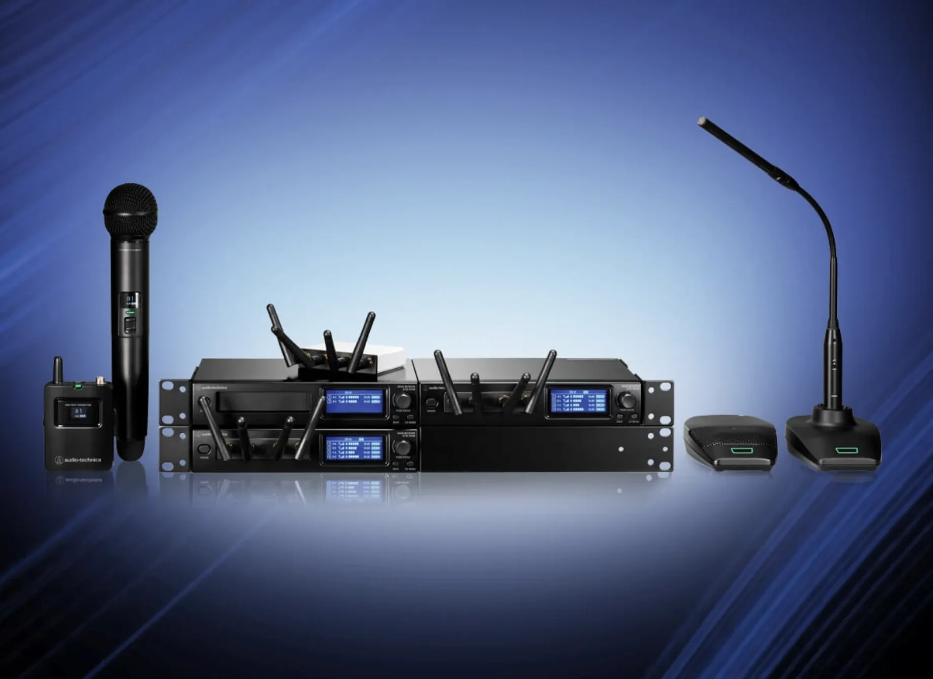 Conjunto de equipamento Audio-Technica: microfone de mão sem fios, recetores de rack, microfone de haste e microfones de superfície, sobre fundo azul.