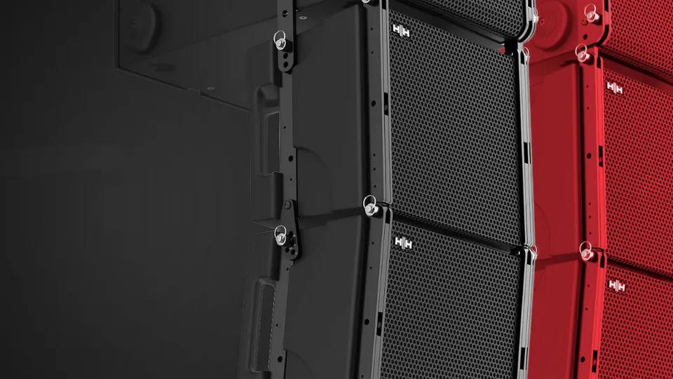 Módulos de line array HH Audio suspensos lado a lado, em preto e em vermelho, vistos de perto.