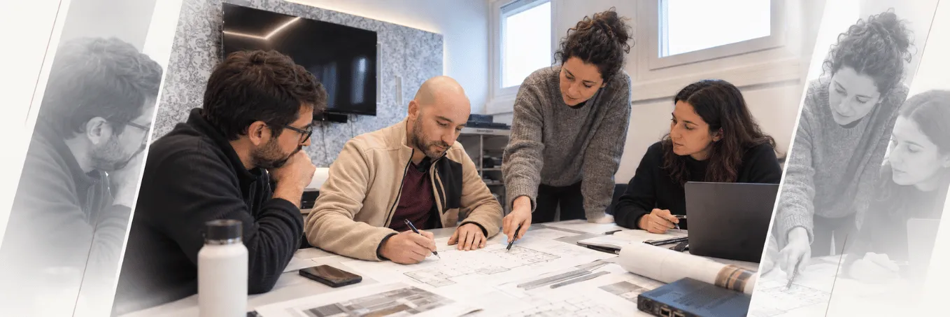 Equipa reunida à volta de uma mesa a rever plantas técnicas: uma pessoa desenha sobre a planta enquanto outra aponta um detalhe.